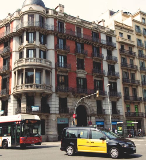 taxi and buses driving past historic hostel building